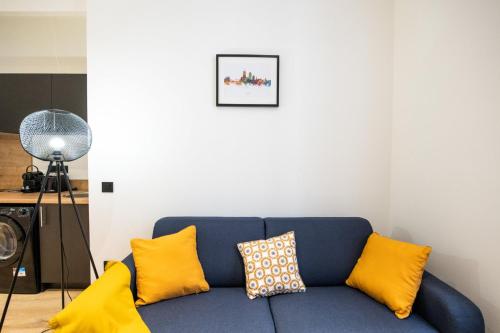 un canapé bleu avec des coussins jaunes dans un salon dans l'établissement L'Opéra 9-Joli studio proche Opéra/Hôtel de Ville, à Lyon