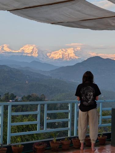 a person standing on a balcony looking at mountains at Indralok Hotel and Sky Garden in Deorāli