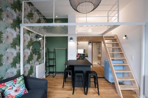 Cette chambre comprend une mezzanine, une table et des chaises. dans l'établissement Le Canopée - Beau studio atypique quais du Rhône, à Lyon