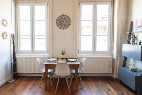 une salle à manger avec une table, des chaises et des fenêtres dans l'établissement L'Indigo- Coup de coeur Canut - Croix Rousse, à Lyon