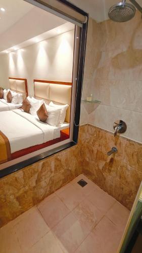 a bedroom with a bed and a shower with a mirror at MM Legacy - A Bergamont Hotel, Kanchipuram in Kanchipuram