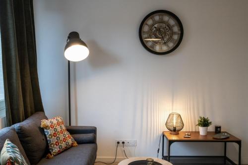 un salon avec un canapé et une horloge au mur dans l'établissement Le Bollier - Charmant appartement au calme, à Lyon