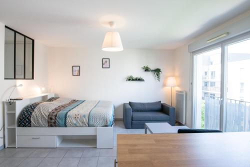 une chambre avec un lit et un canapé bleu dans l'établissement Le Gaïa - Joli appartement au calme 10min du centre de Lyon, à Villeurbanne