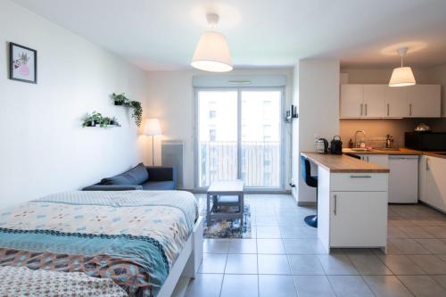 une chambre avec un lit et une petite cuisine dans l'établissement Le Gaïa - Joli appartement au calme 10min du centre de Lyon, à Villeurbanne