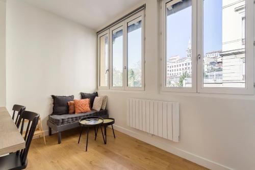 - un salon avec un canapé, une table et des fenêtres dans l'établissement L'Onyx - Beau studio atypique coeur Presqu'île, à Lyon
