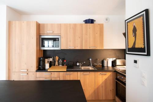 une cuisine avec des armoires en bois et un comptoir noir dans l'établissement Le Cosmo - Premium apartment w/ terrace- Part Dieu, à Lyon
