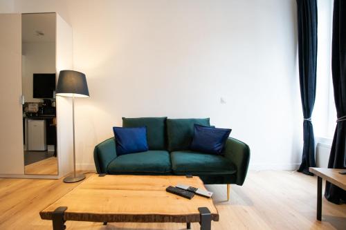 - un canapé vert avec des oreillers bleus dans le salon dans l'établissement Le Romanée - Très joli studio moderne tout confort proche place Valmy, à Lyon