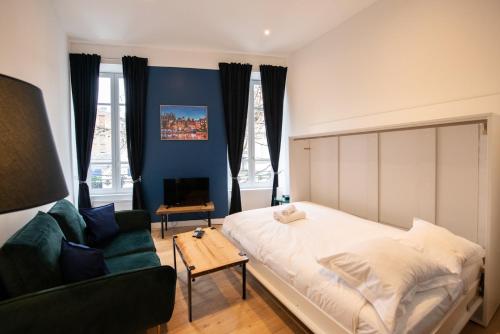 une chambre avec un grand lit et un canapé dans l'établissement Le Romanée - Très joli studio moderne tout confort proche place Valmy, à Lyon
