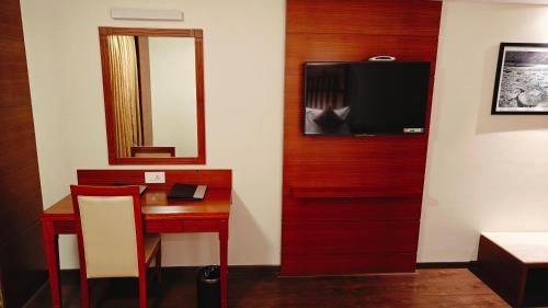 a room with a desk and a television on a wall at MM Legacy - A Bergamont Hotel, Kanchipuram in Kanchipuram