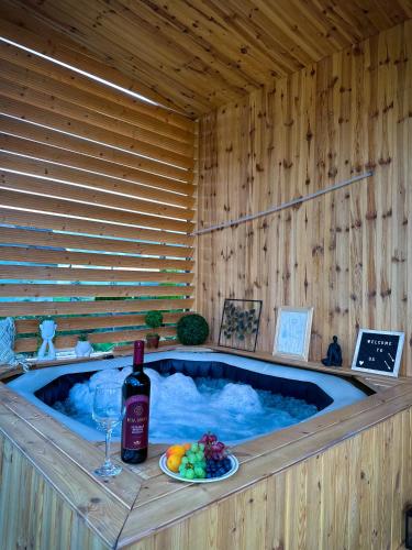 a hot tub with a bottle of wine and a plate of fruit at Vila Miorita in Sebeş