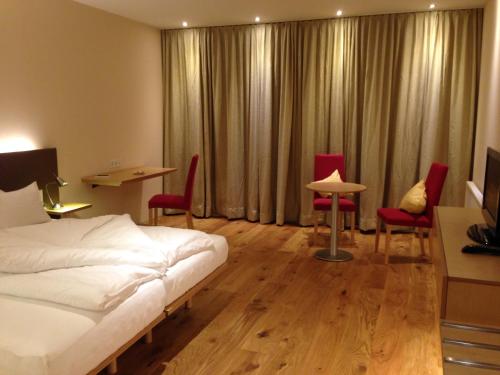 a hotel room with a bed and chairs and a table at Hotel Hoher Freschen in Rankweil