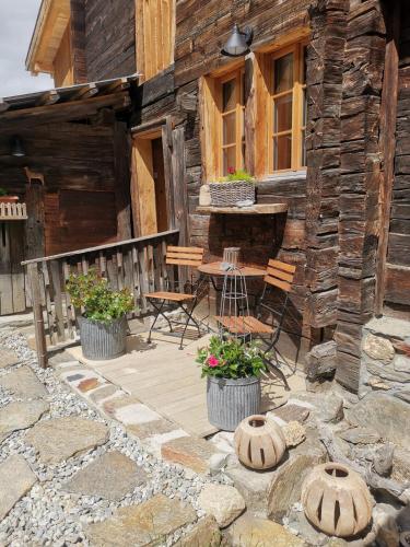 a porch of a log cabin with a table and chairs at Hockmatte in Grengiols