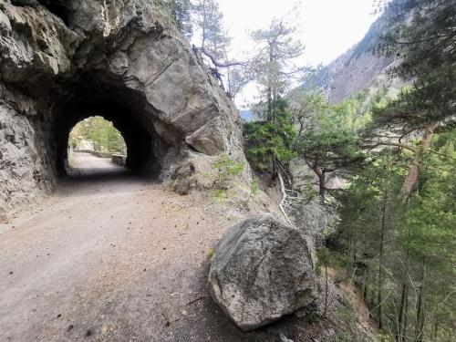a tunnel on a dirt road with a large rock at Hockmatte in Grengiols