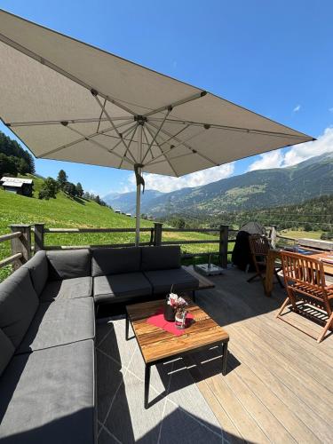 a patio with a couch and a table with an umbrella at Hockmatte in Grengiols