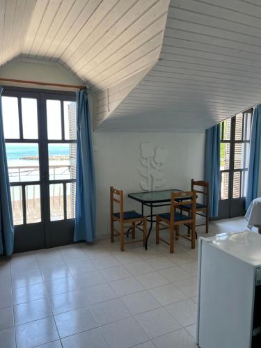 a dining room with a table and chairs and windows at Medusa Apartments in Katelios