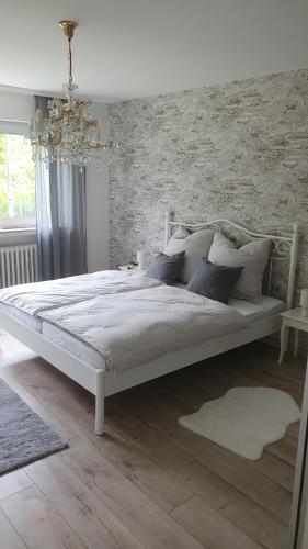 a white bed in a bedroom with a brick wall at Ferienwohnung Am Lollbach in Bad Kissingen