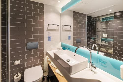 a bathroom with a sink and a toilet and a mirror at Holiday Inn Express Dresden Zentrum by IHG in Dresden