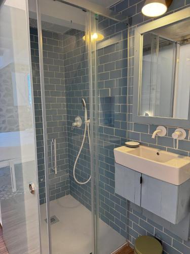y baño de azulejos azules con ducha y lavamanos. en Verdejo - Harbor's Light, en Villajoyosa