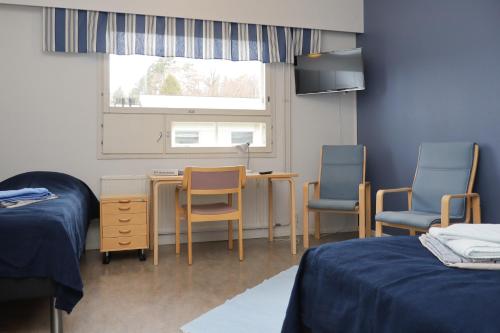 a room with two beds and a desk and two chairs at Eurajoen opisto in Eurajoki