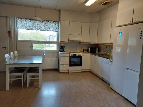 a kitchen with white cabinets and a table and a refrigerator at Eurajoen opisto in Eurajoki