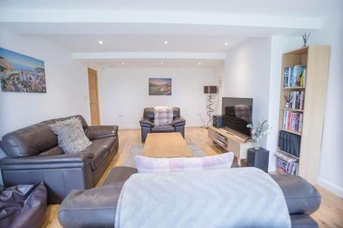 a living room with leather couches and a tv at Superb 2 bedroom town apartment, quiet location in Harrogate