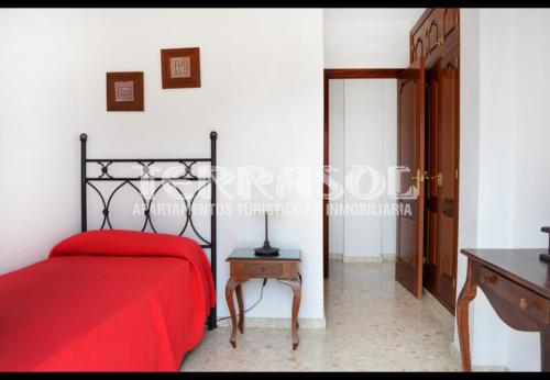 a bedroom with a red bed and a wooden table at Terrasol Azucarera Atico H in Torre del Mar