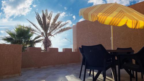 a table and chairs with an umbrella on a patio at Sunset Villa by the Ocean in Ibekhchach