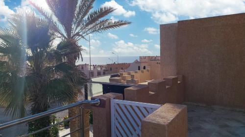 a balcony of a building with a palm tree at Sunset Villa by the Ocean in Ibekhchach