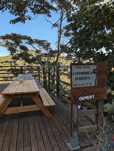a wooden picnic table on a wooden deck with a sign at CROUXETO Chambres d'hôte in Duilhac