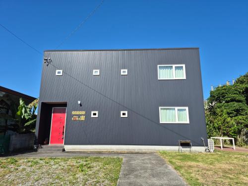 a black building with a red door and a red door at Cottage SORA in Onna