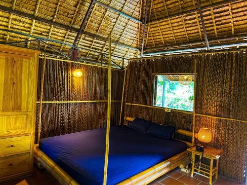 a bed in a bamboo room with a window at Dan Sinh Homestay in Can Tho