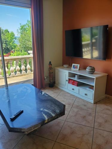 un salon avec une télévision et une table dans l'établissement Villa privée au calme avec gand jardin et terrasse, à Bout-du-Pont-de-Larn