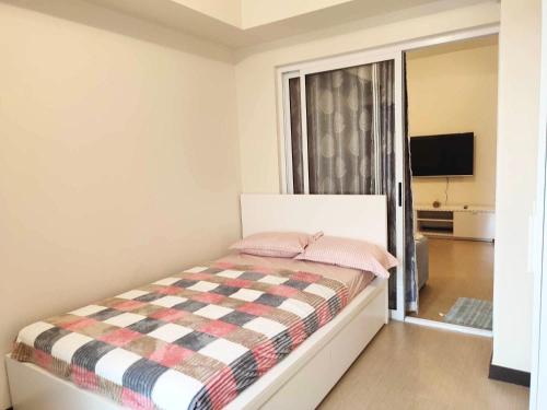 a white bedroom with a bed and a large window at The Intramuros Suite in Manila