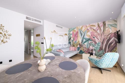 ein Wohnzimmer mit einem Tisch, Stühlen und einem Wandbild in der Unterkunft Design Apartment Flamenco Garden at La Finca Golf - By Oyoostays in Algorfa