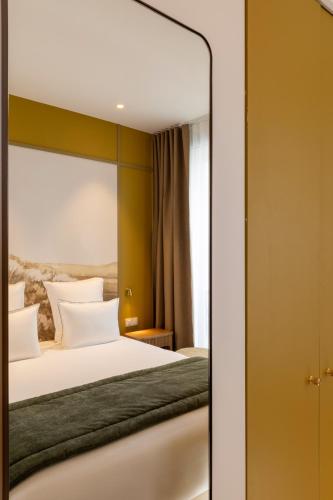 a bedroom with a white bed and a mirror at Hôtel Le Cardinal in Paris