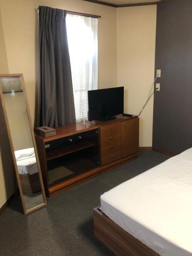 a bedroom with a television and a dresser with a mirror at The entrance to Hakata Island in Imabari