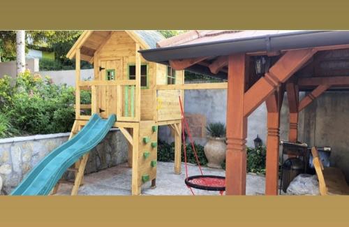a wooden play house with a slide and a surfboard at Brvnara Petra in Berkovac