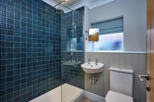 a blue tiled bathroom with a toilet and a sink at The Globe Inn in Wells next the Sea