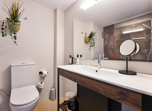 a bathroom with a sink and a toilet and a mirror at Flacalco Hotel & Apartments in Cala Ratjada