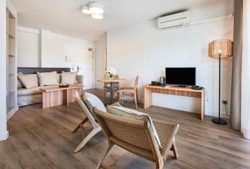 a living room with a couch and a table and chairs at Flacalco Hotel & Apartments in Cala Ratjada