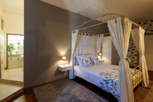a bedroom with a canopy bed and a bathroom at Domaine de Seugnac in Pons