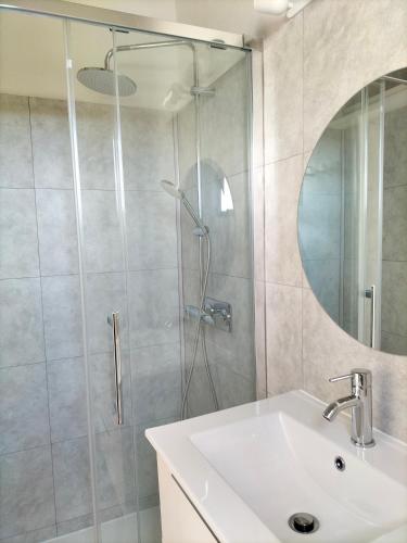 une salle de bain avec une douche avec un lavabo et un miroir dans l'établissement Studio vue mer à Porticcio proche aéroport Ajaccio, à Porticcio