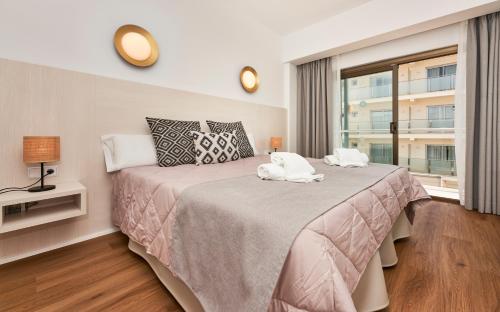 a bedroom with a large bed with a window at Flacalco Hotel & Apartments in Cala Ratjada