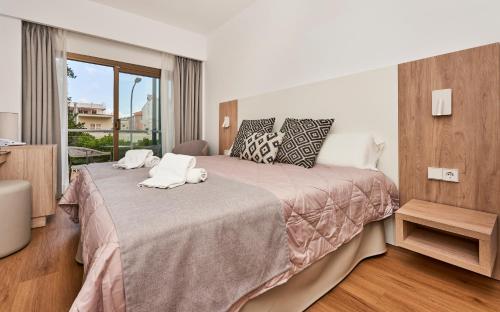 a bedroom with a bed with towels on it at Flacalco Hotel & Apartments in Cala Ratjada