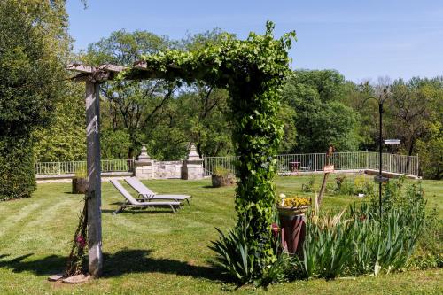 an arch covered in ivy with a bench in a park at Domaine de Seugnac in Pons