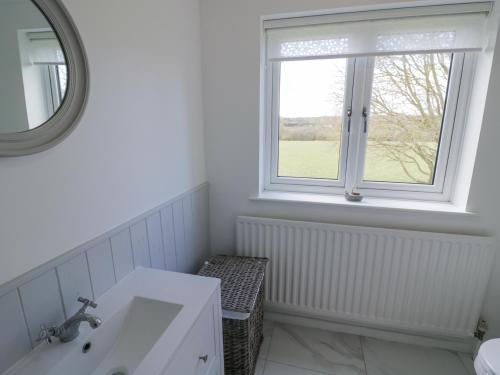 a white bathroom with a sink and a window at New House Farm in Leamington Spa