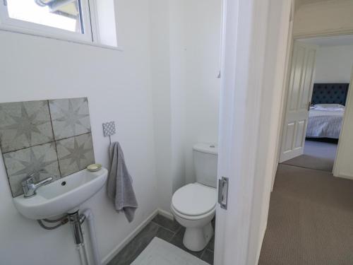 a white bathroom with a toilet and a sink at New House Farm in Leamington Spa