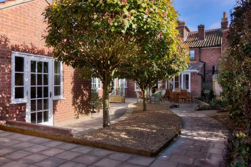 two trees in the courtyard of a brick building at The Globe Inn in Wells next the Sea