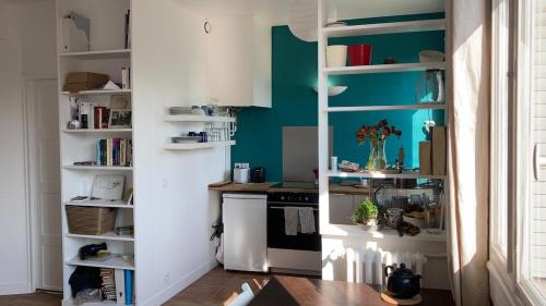 - une cuisine avec des murs verts et des étagères blanches dans l'établissement studio lumineux avec vue sur le canal, à Paris