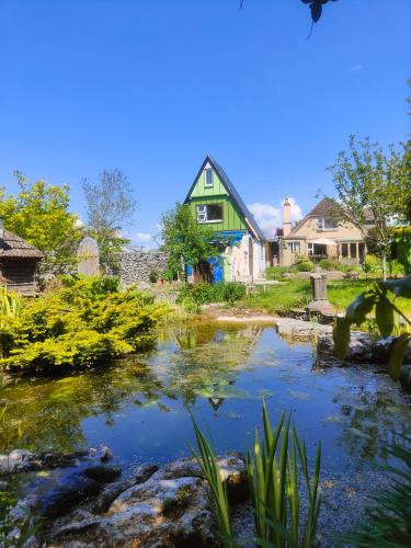 a house with a pond in front of a yard at Bohemian Bell Tent in Kinvara County Galway in Kinvara